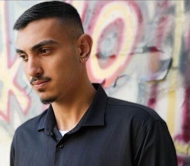 עילאי גניש בצילום פורטרט ליד קיר גרפיטי